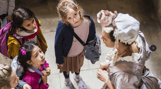 Group of children talking to an actor in historic fancy dress